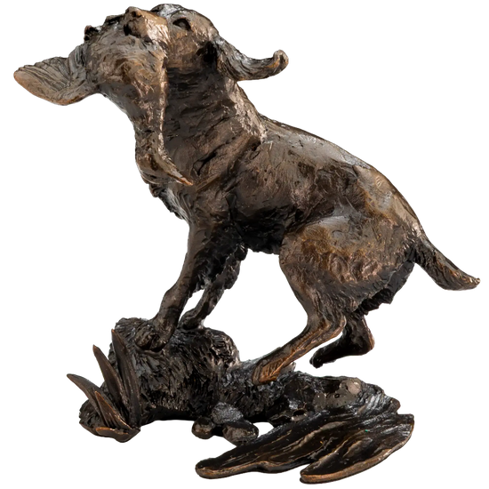 A bronze sculpture of a dog standing over a fallen animal on a textured base, shown against a plain white background.