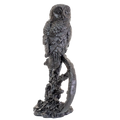 Statue of an owl perched on a branch against a white background