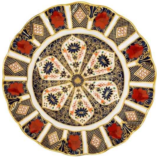 An ornate round ceramic plate with a scalloped rim, featuring a detailed floral and geometric pattern in navy blue, gold, white, and terracotta red.